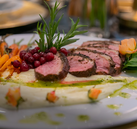 Zbliżenie na eleganckie danie z plastrami mięsa, żurawiną i rozmarynem na białym talerzu