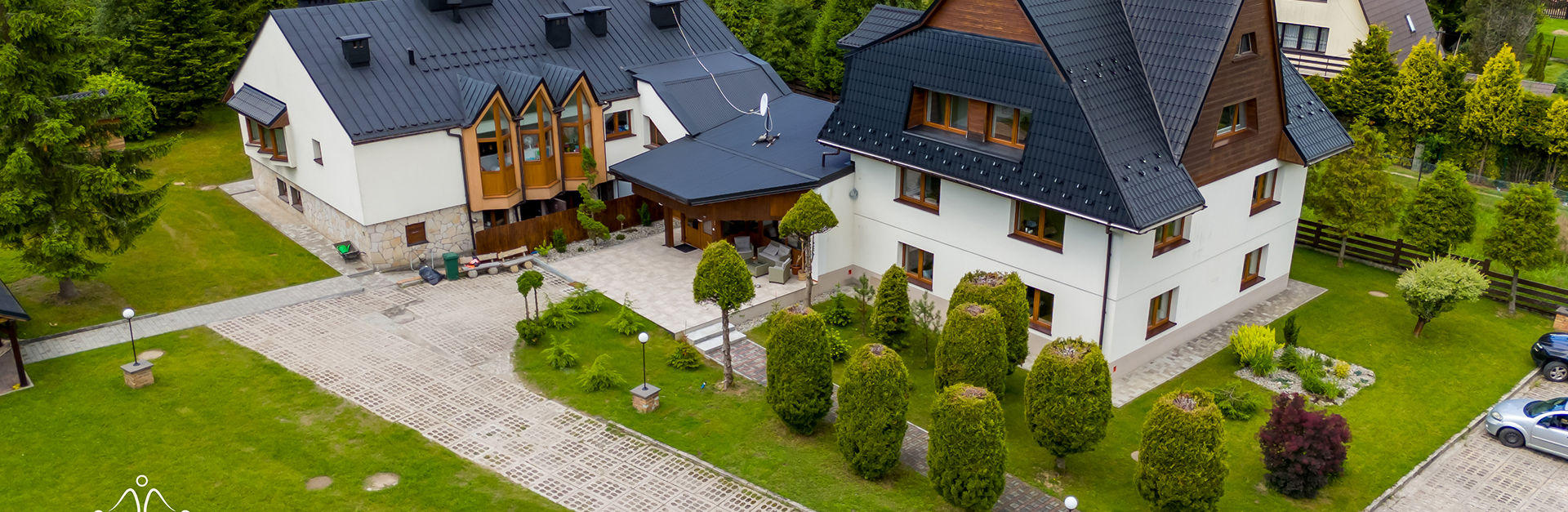 Widok z drona na ośrodek Cisza z budynkiem i zadbanym ogrodem, ścieżkami oraz zielenią wokół